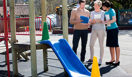 Adults inspecting playground slide for safety